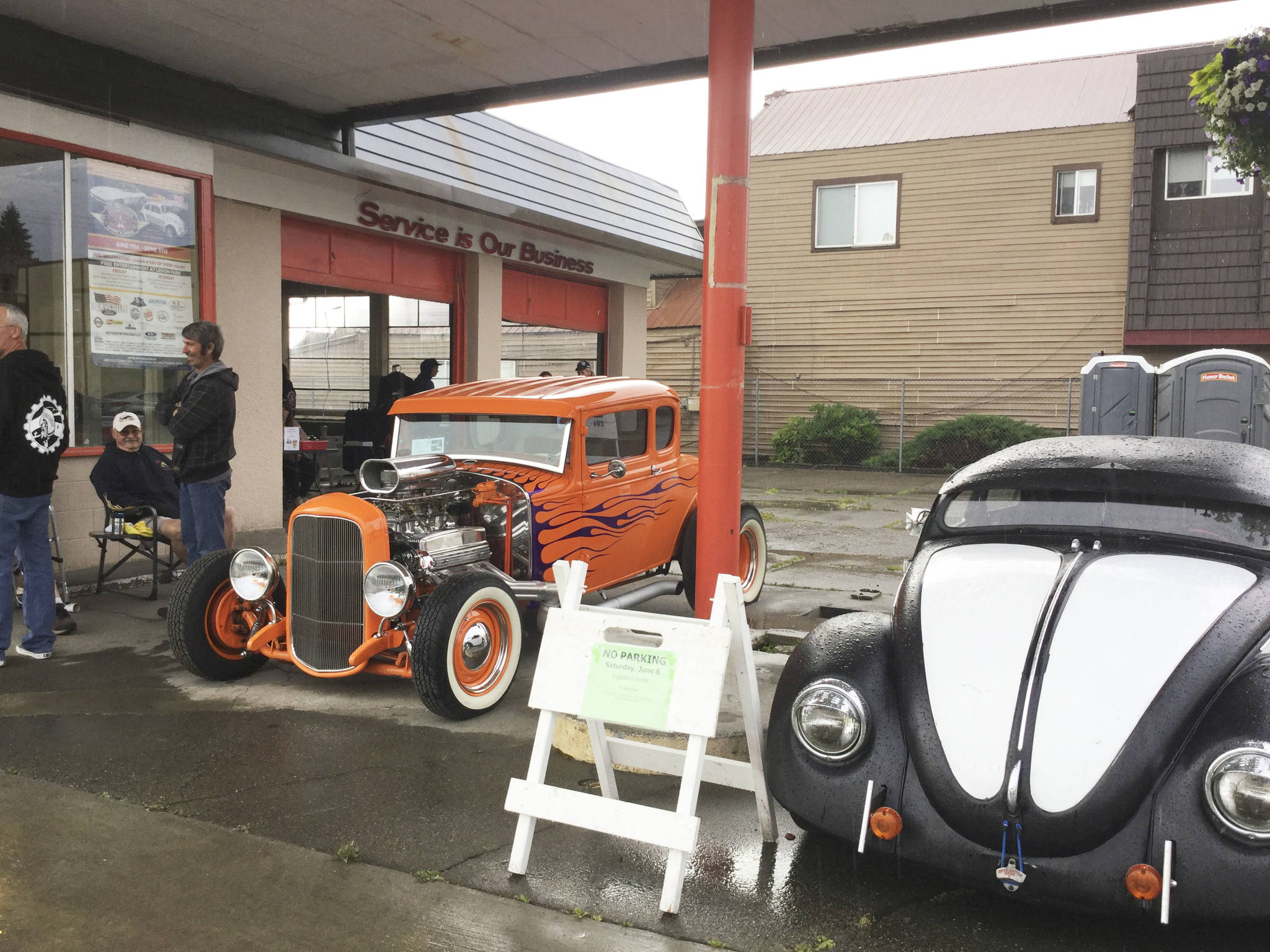 Steve Holden of Marysville, seated, and his Dick’s Drive-In orange 1931 Ford Model A Coupe take shelter from the rain at the Old Howell service station the first night of the 20th annual Show ‘n Shine Car Show on Olympic Avenue.