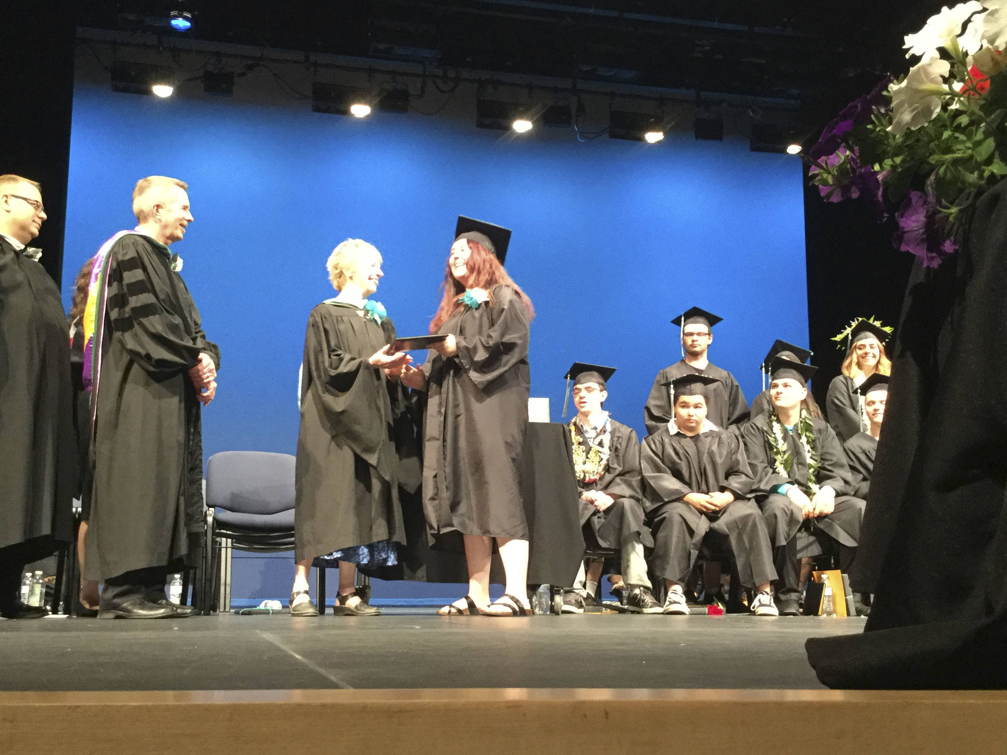Weston High School graduate Alexis Myers receives her diploma from school board member Judy Fay, a former teacher, and fellow board members Jeff Huleatt and Jim Weiss.