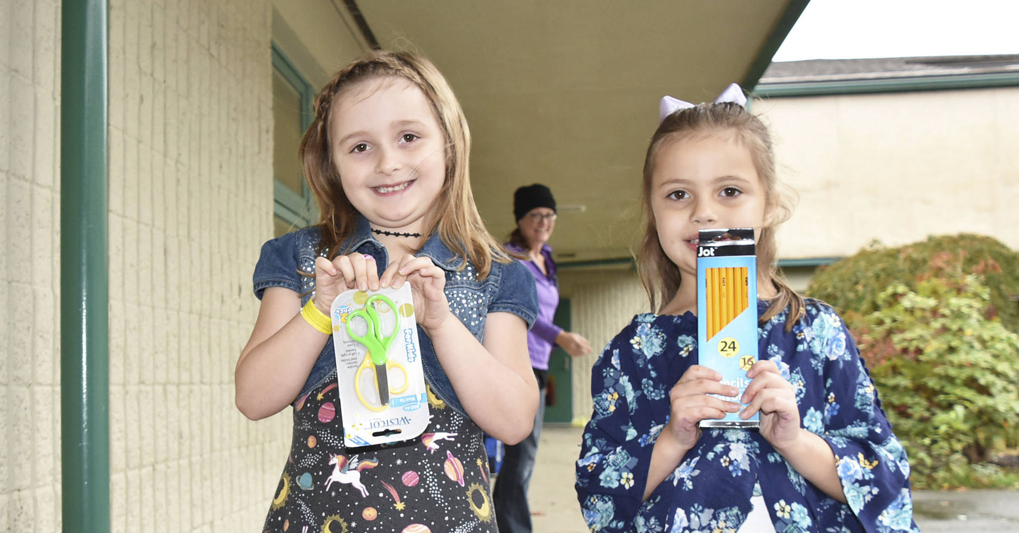Kent Prairie Elementary kindergartners Jade Knudson and Lillyann Brogan show some of the school supplies the students have gathered over the past month that are being donated to children in Uganda.