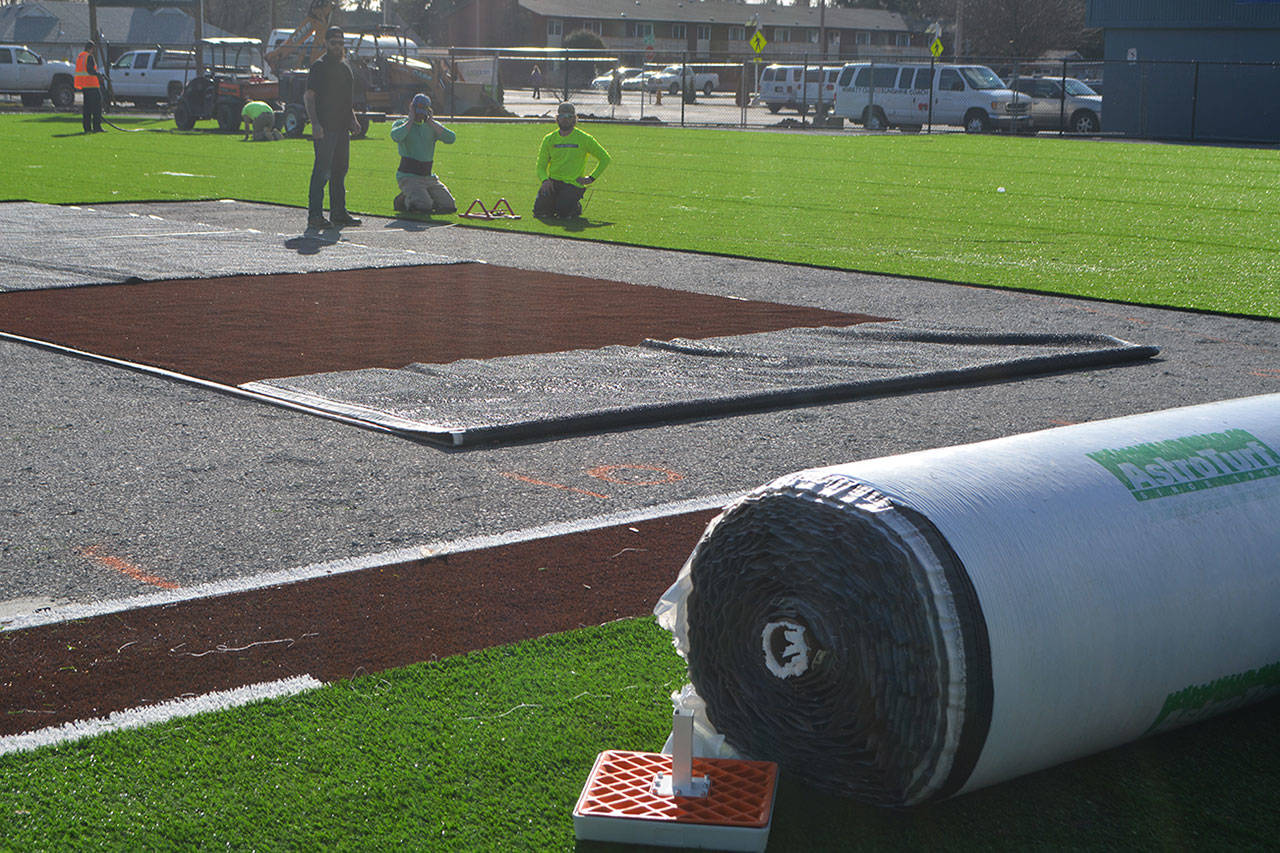 Workers put the astroturf in place.