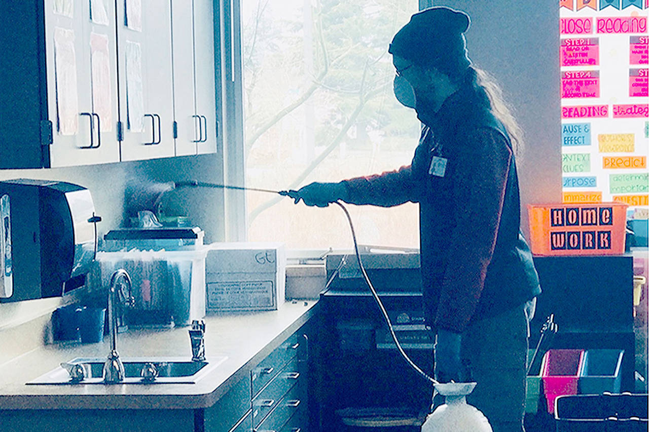 COURTESY Photo                                A custodian sprays a surface with disinfectant at Grove Elementary in Marysville. Ten minutes later the spray is wiped down. Work will continue into the evening so both schools can reopen Wednesday.