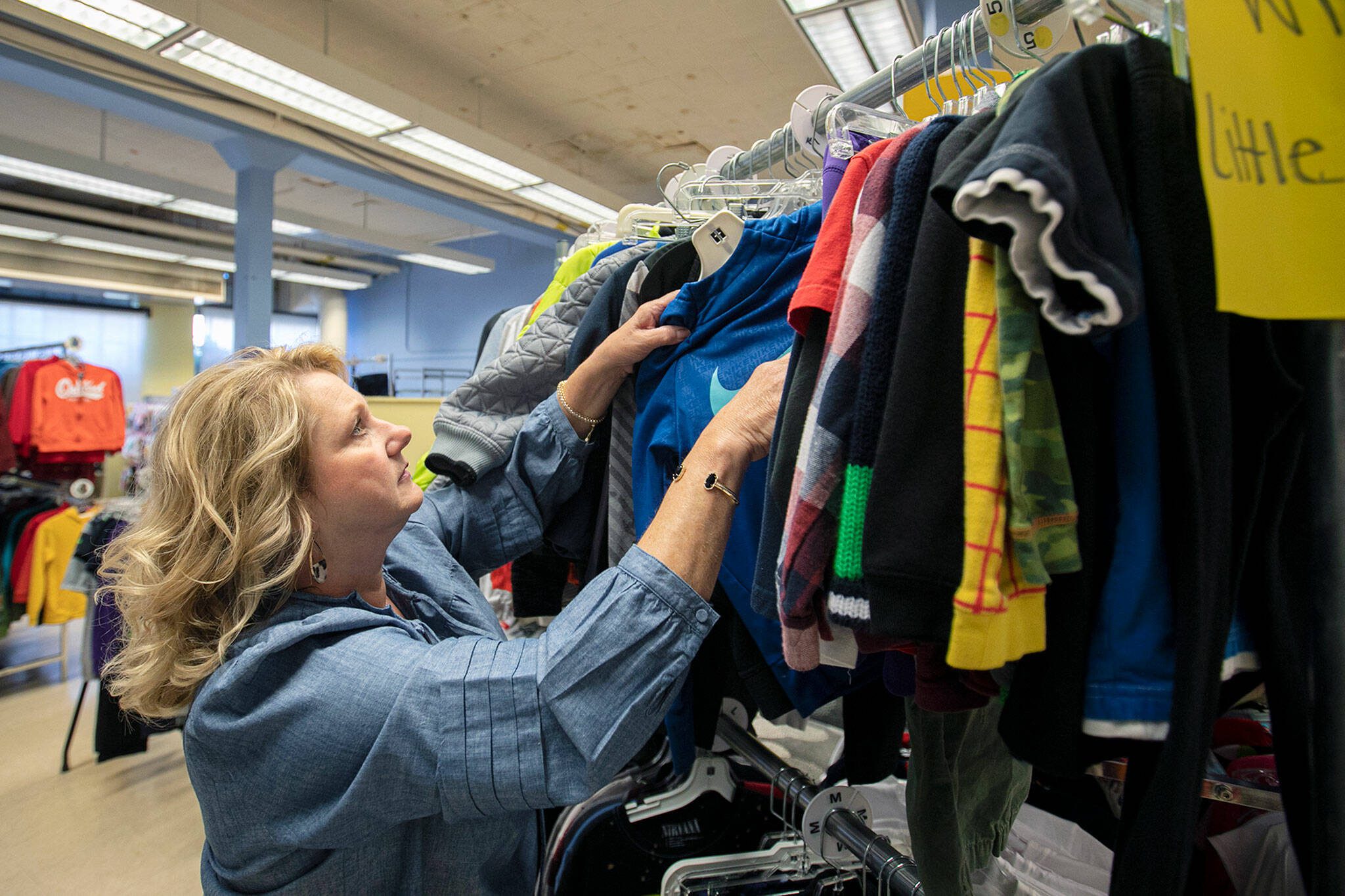 Director and Cofounder Kimberly Meno hangs up some new clothing at Arlington Kids; Kloset on Nov. 17, in Arlington. (Ryan Berry / The Herald)