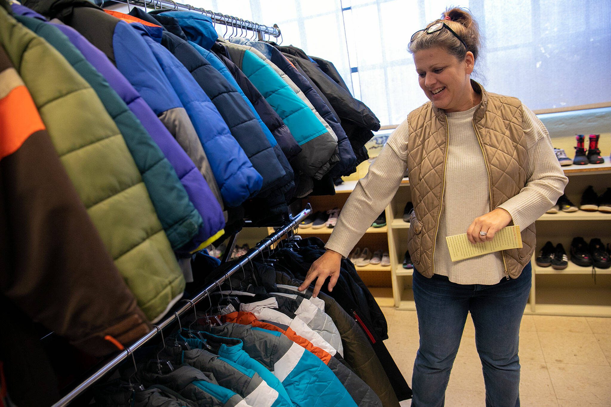 Site Manager Larissa Spencer sifts through some newly donated jackets at Arlington Kids’ Kloset on Nov. 17, in Arlington. (Ryan Berry / The Herald)