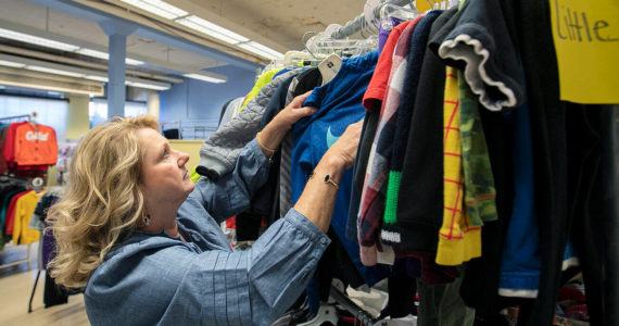 Director and Cofounder Kimberly Meno hangs up some new clothing at Arlington Kids’ Kloset on Thursday, Nov. 17, 2022, in Arlington, Washington. (Ryan Berry / The Herald)