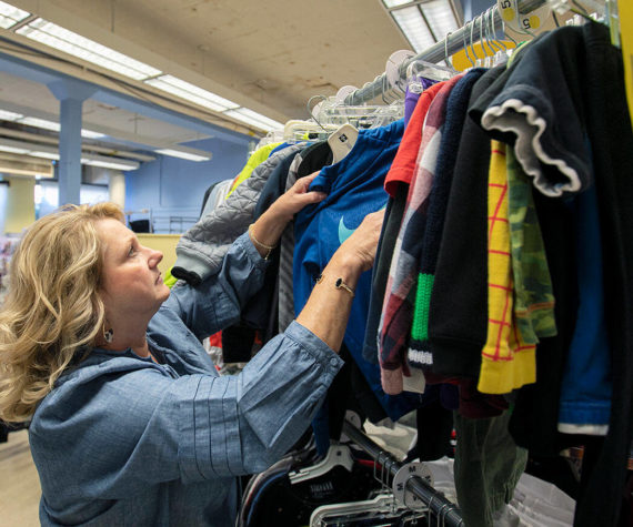 Director and Cofounder Kimberly Meno hangs up some new clothing at Arlington Kids’ Kloset on Thursday, Nov. 17, 2022, in Arlington, Washington. (Ryan Berry / The Herald)