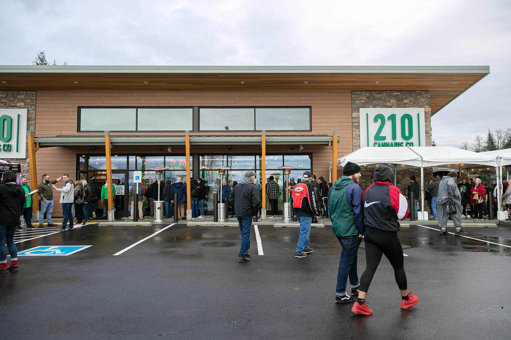 A line already wrapped around the building continues to grow as people arrive during 210 Cannabis Co’s grand opening Dec. 10, in Arlington. (Ryan Berry / The Herald)