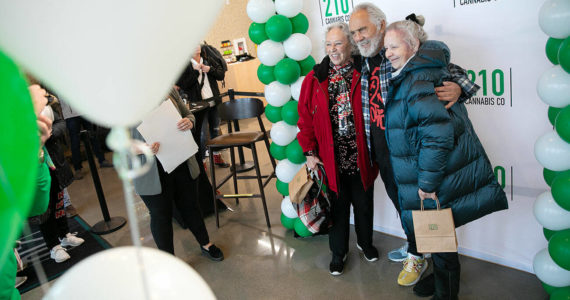 Carla Fisher and Lana Lasley take a photo together with Tommy Chong during 210 Cannabis Co’s grand opening Saturday, Dec. 10, 2022, in Arlington, Washington. Fisher and Lasley waited in line solely to get a photo with Chong. (Ryan Berry / The Herald)